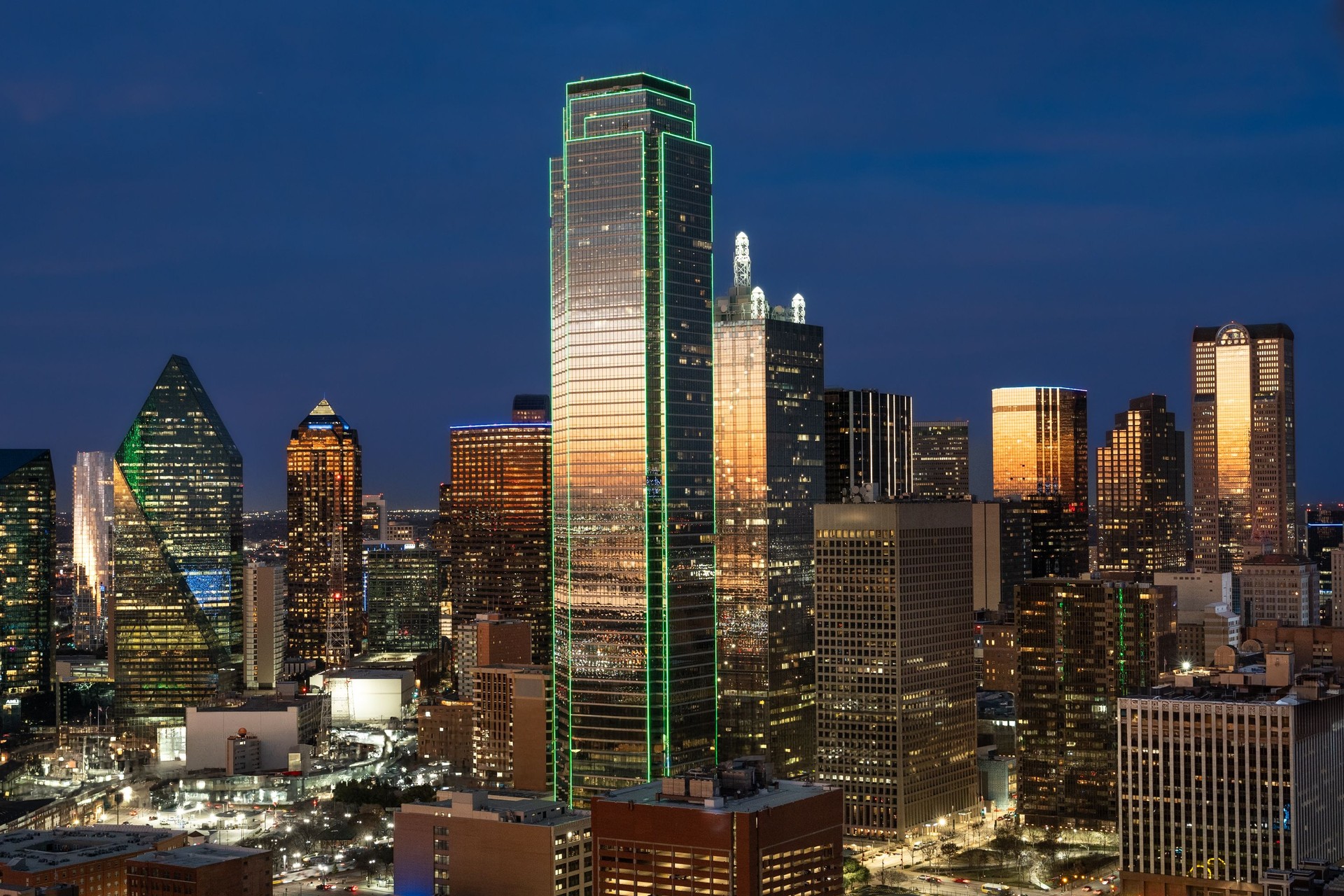 Dallas, Texas in USA downtown cityscape skyline with modern glass buildings and construction crane against cloudy sky in summer with trees and street light